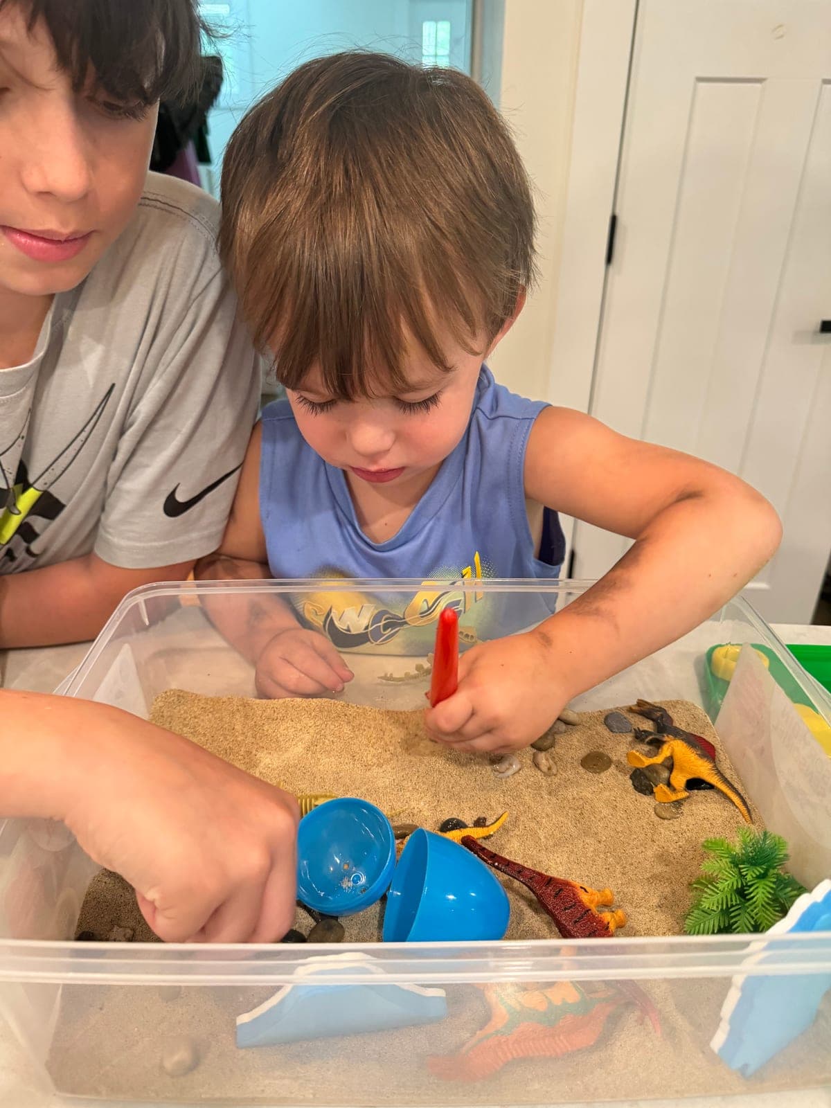 Children digging for dinosaurs in a sand sensory bin